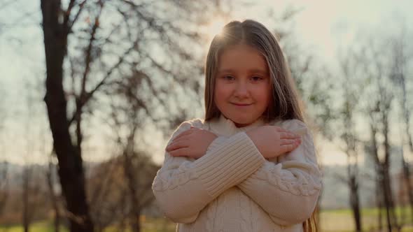 Portrait cute child looking at camera stay at autumn park outdoors. Pretty female girl school age alt