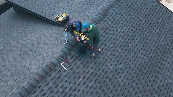 Aerial View of a Two Workers on the Roof Installing the Iron Chimney alt