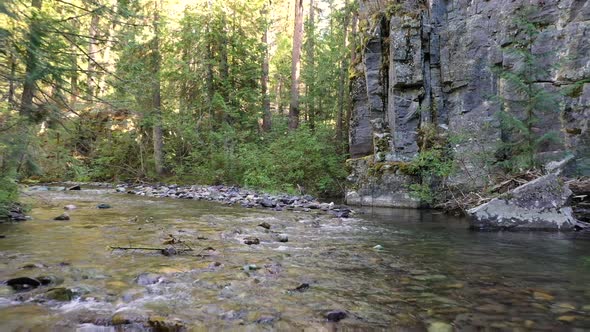 Shallow Water Flowing Through Rocky River With Rocky Cliffs In The Forest. - aerial pullback alt