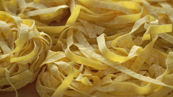Close up of raw fresh pasta rotate on board. Fettuccine pasta. Italian Cuisine. Food background