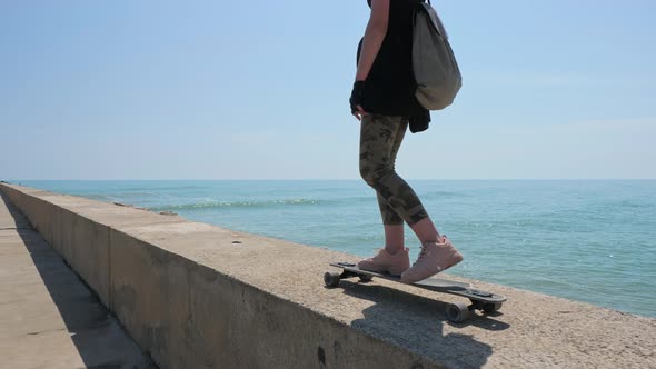 A Beautiful Blonde Girl on Skateboard in Summer Hot Day on Seafront alt