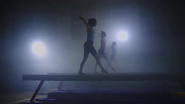 Three Female Gymnasts is Performing Program on Balance Beam Synchronous Sport Team is Training alt