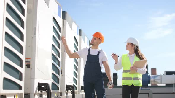 Two Happy Engineers are Passing By the Air Conditioners and Doing Their Inspection alt