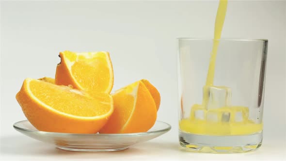 Fresh Orange Juice Is Poured Into A Glass And A Plate With Chopped Orange On A White Background