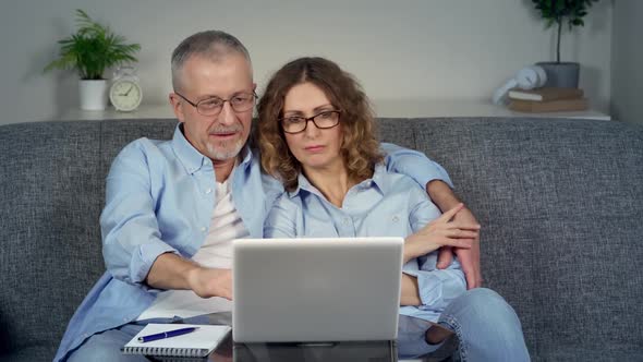 A Happy Middleaged Couple Excited to Win Online on a Laptop