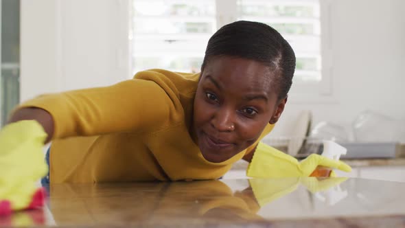 Happy african american female cleaning countertop in kitchen alt