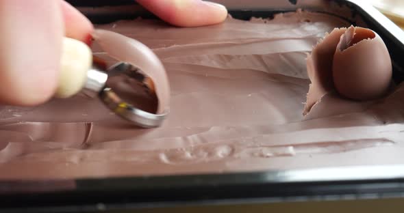 An artist in a studio carving soft brown modeling clay with a sharp hand tool into a satisfying shav alt