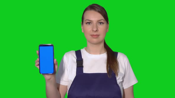 Woman Builder in Blue Overalls Hold Mobile Phone with Green Screen