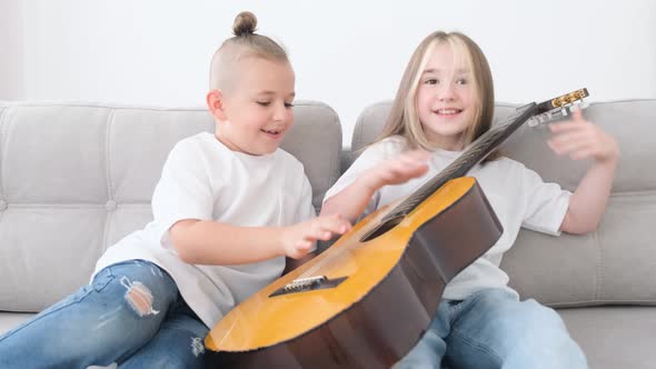 Brother and Sister Have Fun Sitting on the Couch They Play the Guitar alt