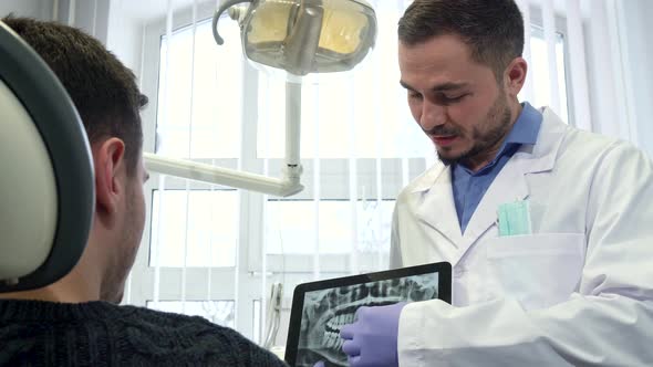 Dentist Shows Male Client X-ray on His Tablet
