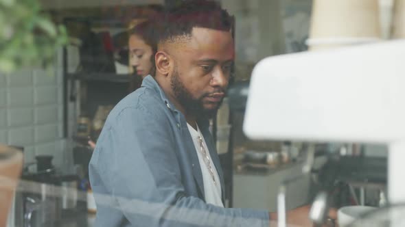 Happy african american male cofe owner and biracial female barista making coffee alt