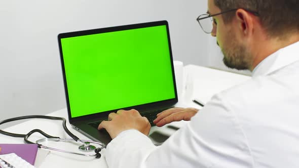 Close-up of Doctor Scrolling Data on Chroma Key Laptop at Hospital alt