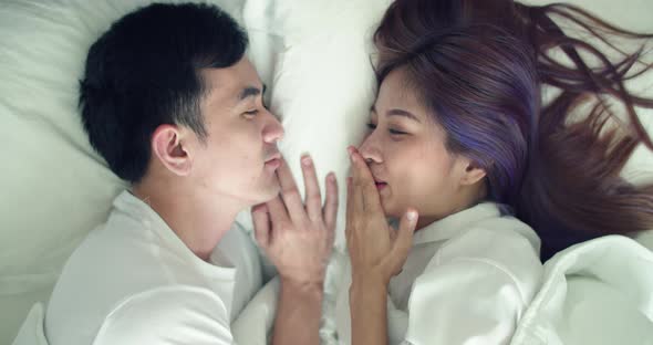 Happy Asian husband and pregnant wife spend time together in the bedroom in the morning.