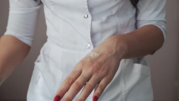 Close Up of Professional Beautician Shows How to Applying Body Lotion Cream on Hands alt