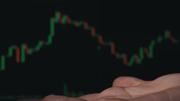 Stack of Dollars Falls Into a Hand Against the Background of a Stock Market Chart alt