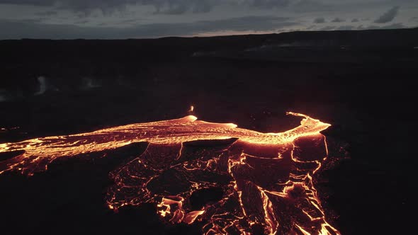 Drone Towards Flowing River Of Molten Lava Under Cloudy Sky alt