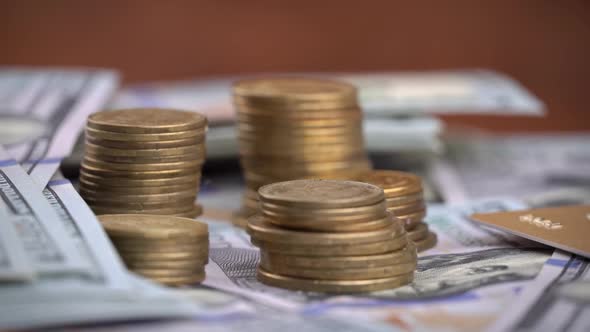 Columns of Coins are Spinning Against the Background of One Hundred Dollar Bills alt