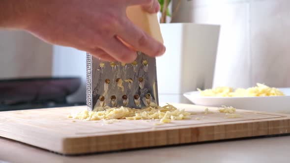 A Man Rubs Cheese on Metal Grater for Freezing and Further Cooking Pizza Pasta