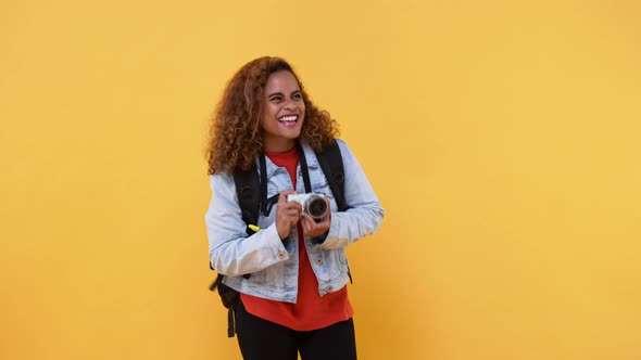 Amazed solo woman tourist taking photo with camera in yellow isolated studio background