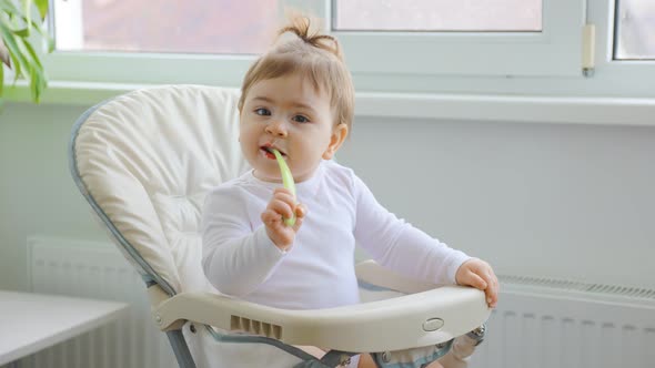 Cute Baby Girl Playing with Plastic Spoon Near the House Window alt