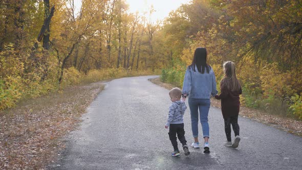 Beautiful Young Woman with Two Children Walking in Forest alt