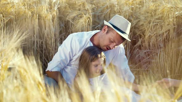 Happy family with little daughter having picnic in wheat field in summer alt