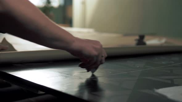 Tailor at a fabric factory makes calculations and measurements before cutting