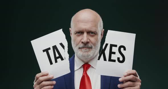 Businessman breaking a sign with taxes word, tax cut and finance concept