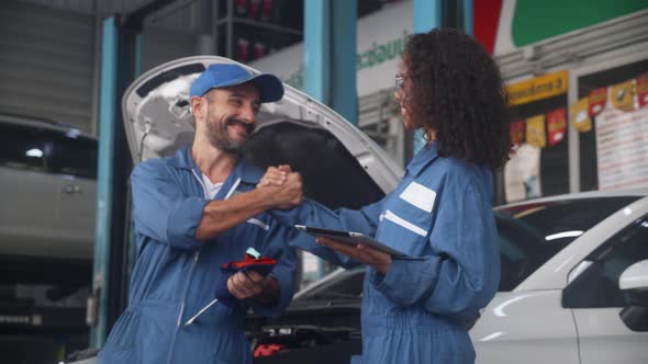 Team of mechanic with man and woman holding tablet computer in uniform talking and handshake. alt