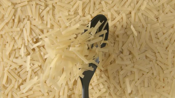 Black plastic spoon with a pasta falls on a pasta