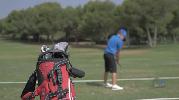 Chico practica golf en un campo. Bolsa con palos de golf. Slowmotion alt
