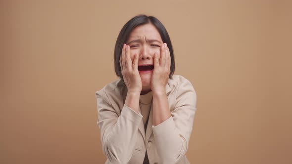 Asian business woman sad and screaming isolated over beige background. 4K video