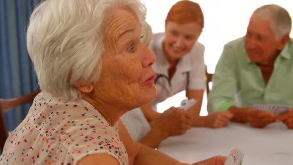 Senior woman talking to senior man while sitting at dinning table alt
