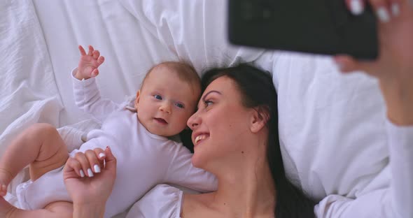 Portrait a Beautiful Young Mother with a Baby Talking on a Video Call on a Mobile Phone