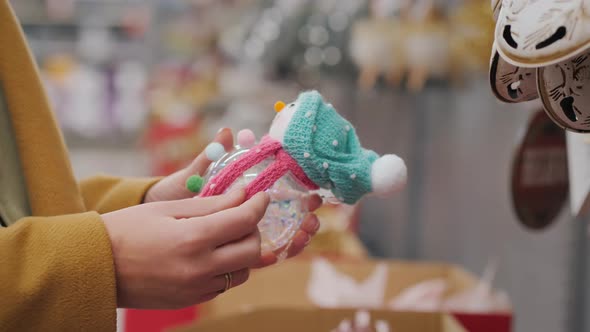 The Buyer Holds a Toy Snowman in His Hands  Chooses Decorations for the Christmas Tree alt