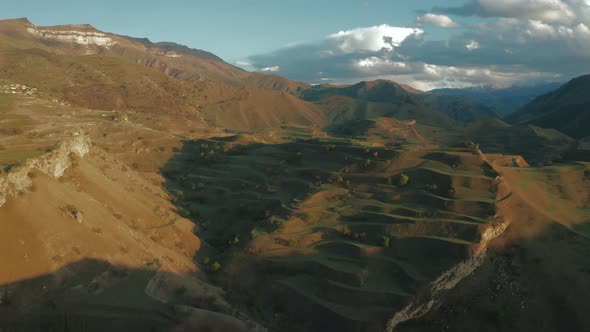 Aerial view of mountain hills, terraces on sunset, countryside landscape with tractor