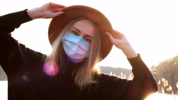 Caucasian Blonde Woman with Beige Hat in Black Sweater Wear Protective Mask in the Countryside alt