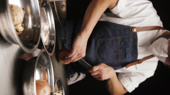 Vertical Shot Of A Chef Wearing Apron And Mask, Cutting Fresh White Onion In The Kitchen. dolly-in, alt