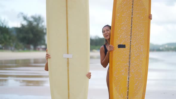4K Portrait of Asian woman friends holding surfboard on tropical beach at summer sunset. alt
