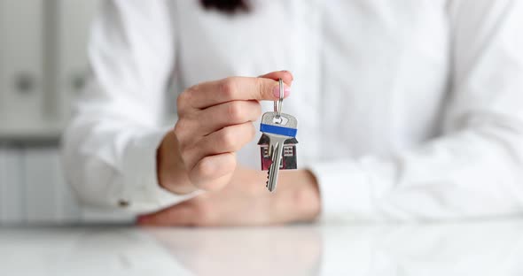 Person Holds Key to House on Key Chain in Shape of House alt