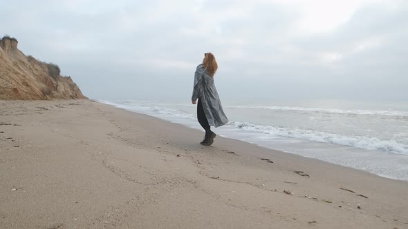 Attractive Redhead Woman in Coat Walking on the Wild Autumn Beach alt
