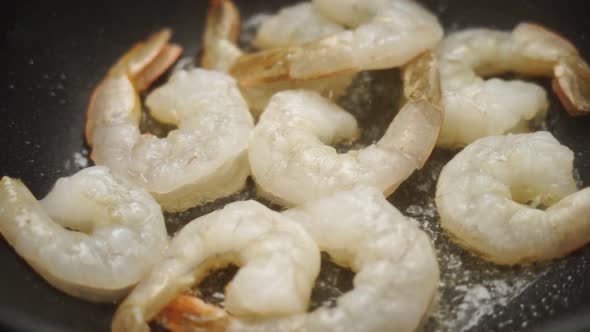 Unrecognizable cook frying prawns in pan with hot oil alt