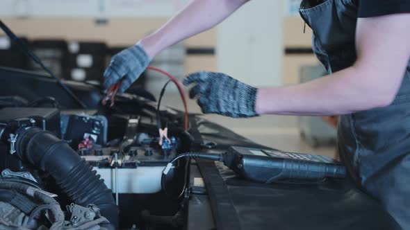 A Mechanic at a Car Service Station Checking the Battery alt