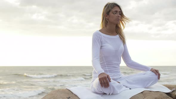 beautiful young woman making yoga position on the beach at the sunset alt