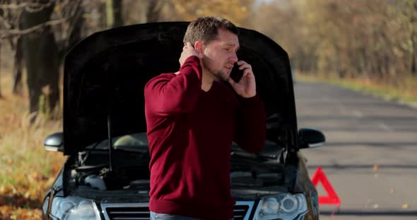Young Unhappy Man Using Smartphone Calling Car Assistance Services Standing By Breakdown Automobile alt