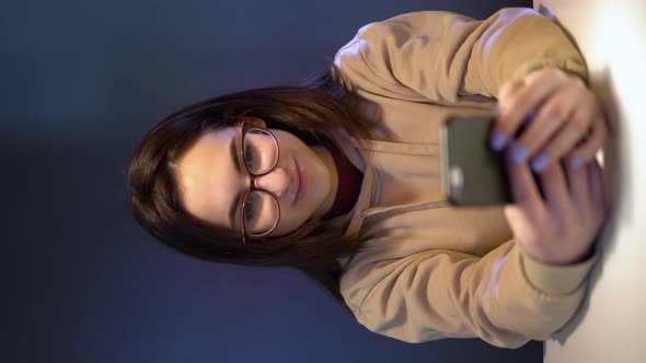 A Young Woman with a Phone Sits at a Table. A Girl Sits at Cafe at a Table with a Smartphone alt
