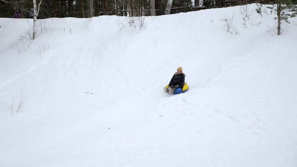Young Woman Is Sliding From Snow Hill at Tubing in Slow Motion. alt