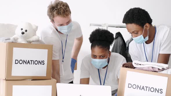 Volunteers Wearing Masks Sorting Clothes Donations During Pandemic alt