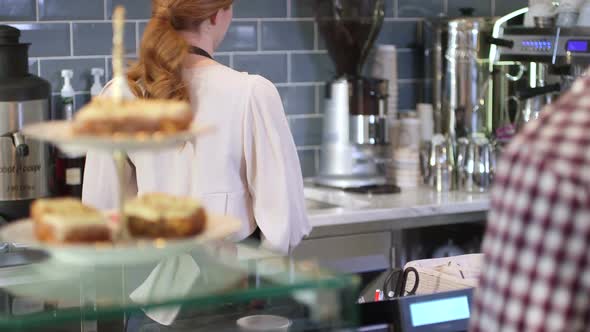 MS TU Mid adult woman giving disposable cup to customer in cafe / London, United Kingdom