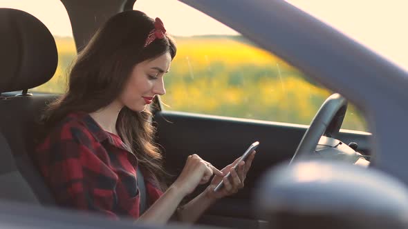 Charming Woman Using Smartphone While Driving Car alt
